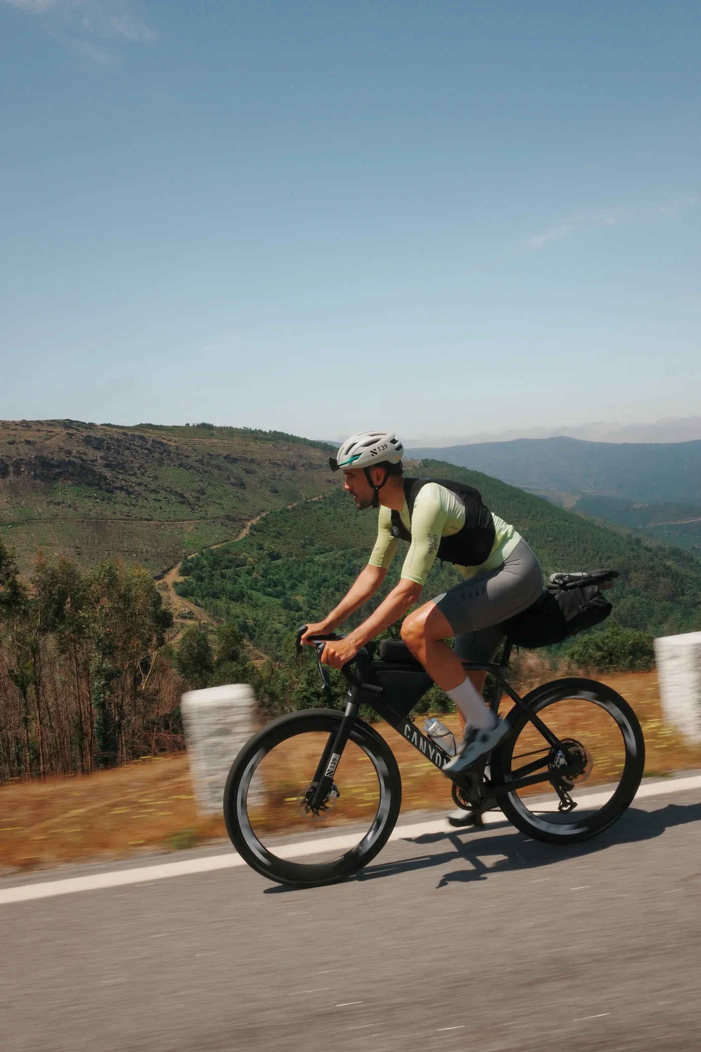 A cyclist climbs a lonely mountain road above a green valley in northern Portugal
